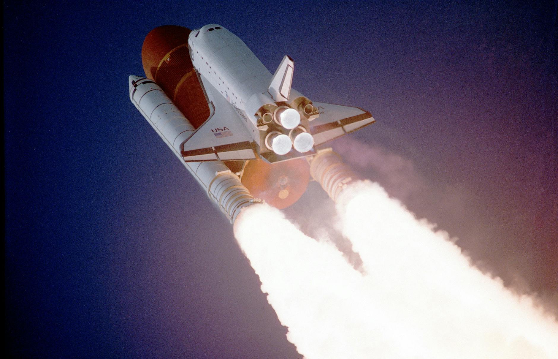 An upward view of a rocket launch against a blue sky.